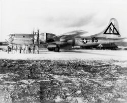 一架大型四发动机飞机停在跑道上，前面站着九名机组人员。