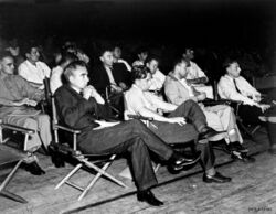 一群身穿衬衫的男子坐在折叠椅里，面朝一个方向，聚精会神。